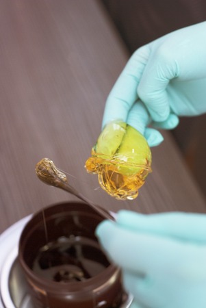 Depilatory sugar paste, The woman, in the beauty salon, takes out from the jar a pasta for a sugaring, yellow color.の写真素材