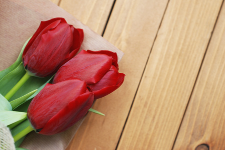 Three Red Tulip Flower Bouquet over Wooden Rustic Background with Copy space. Spring or Easter Compositiob.の写真素材