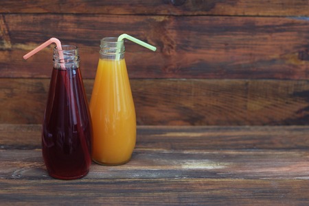 Delicious Orange and Red Grape Juices in Bottles on rustic Wooden Background.の写真素材