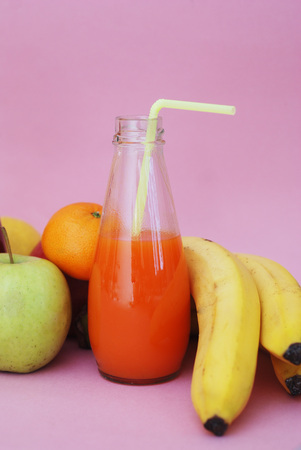 Fresh Juices Red Green Yellow Tropical Fruits Strawberry Apple Kiwi Orange Banana Pine Apple Pomegranate Grape Selective focus Bottles Pink Backgroundの写真素材