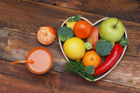 Fruits and Vegetables in Heart shaped Wooden Box. Broccoli, apples, Pepper, tangerine over Wooden Background. Banner. Health food Concept.の写真素材