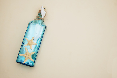 Nautical Theme Backdrop, Decorative Bottle with Shells, Starfish on Neutral Ivory Background. Place for text. Selective focus.の写真素材