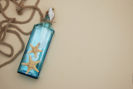 Nautical Theme Backdrop, Decorative Bottle with Shells, Starfish on Neutral Ivory Background. Place for text. Selective focus.の写真素材