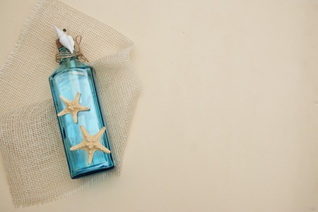 Nautical Theme Backdrop, Decorative Bottle with Shells, Starfish on Neutral Ivory Background. Place for text.の写真素材