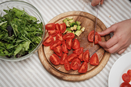 Cutting Red Tomato on Wooden Board. Process of Preparing Healthy Salad.の写真素材