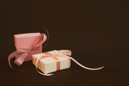 Two Gift Boxes with a pink bow Isolated on Brown Background. Gift, birthday. Sale Conceptの写真素材