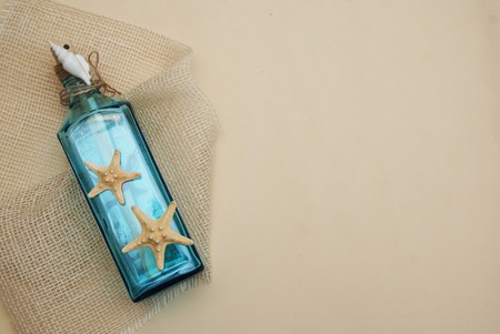 Nautical Theme Backdrop, Decorative Bottle with Shells, Starfish on Neutral Ivory Background. Place for text.の写真素材