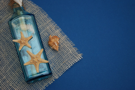 Nautical Theme Backdrop, Decorative Bottle with Shells, Starfish on Depp blue Background.Copy Space.の写真素材