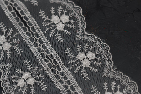 White Lace Embroidered Border on Dark Surface. Lace Texture Background on Dark Board.の写真素材