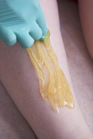 Removing Hair on Women's legs. Procedure sugaring in a beauty salon. Sugar depilation. Depilatory sugar pasteの写真素材