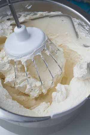 Closeup of electric mixer with whipped smooth cream for cake. Batter being whipped. Mixing white dough in bowl.の写真素材