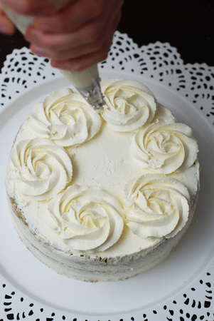 Women Hand Decorating Cake with a pastry bag with White Cream. Decorating Cakeの写真素材