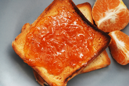 Fresh Toasts with Homemade Orange Jam on Gray Plate over Wood.の写真素材