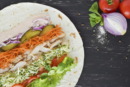 Homemade Shawarma with Chicken Meat fillet and Fresh Vegetables over Wooden Black Board. Cooking Proces.Healthy Food.の写真素材
