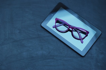 Eyeglasses on Tablet and Mobile Phone over Dark Background with copy space.の写真素材