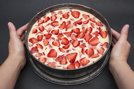 Female Hands Holding Delicious Fruit Strawberry Cheesecake over Black Background.
