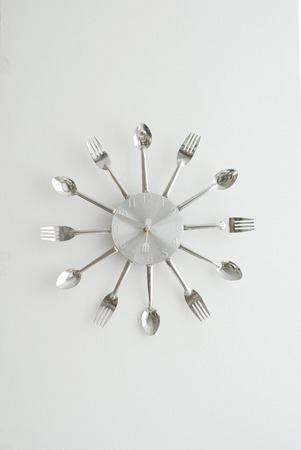 Silver Decorative Clock with spoons and fork, isolated on Gray Wall