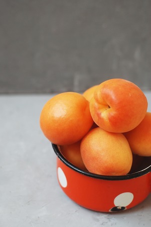 Fresh Apricot isolated on gray background in rustic red metal cupの写真素材