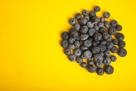 Heap of blueberries isolated on yellow colorful background. Summer vibe fruit berry with copy space.の写真素材