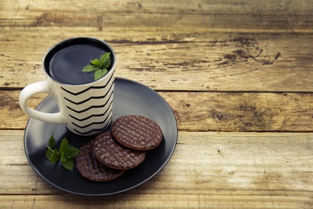 Chocolate cookies with a cup of tea on old wooden background.の写真素材