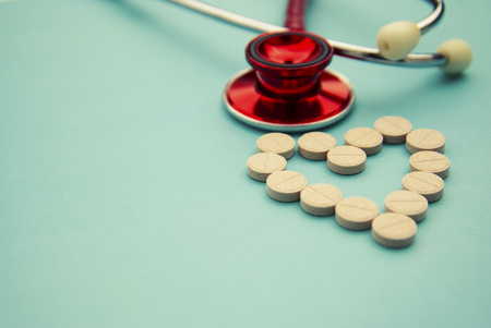 Red stethoscope with tablets, pills on blue background.の写真素材