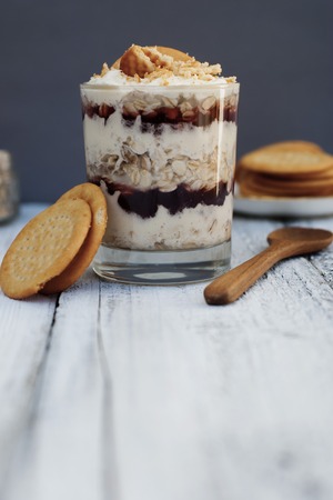Oatmeal granula breakfast with cream in glass. Layered healthy food. Rustic background.の写真素材