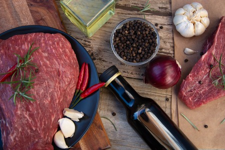 Raw meat, beef steak on rustic wooden table with spices. Food ingredients.の写真素材