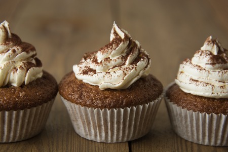 Chocolate cupcakes with whipped cream on rustic wooden table.の写真素材