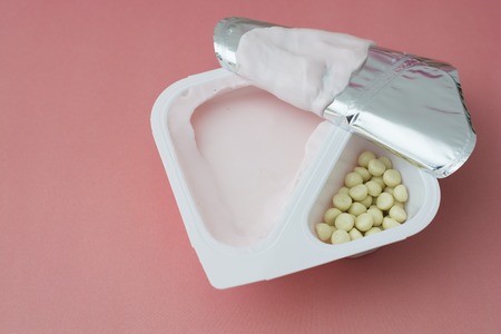 Healthy yogurt in plastic cup with granola and cereal over pink or coral background isolated.の写真素材