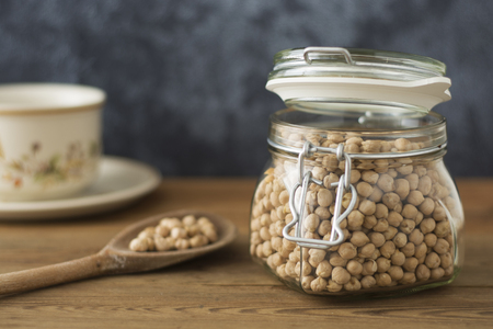 Dried chickpeas in glass jar on wooden background with copy space. Isolated.の写真素材