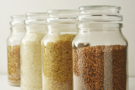 Various raw cereals, grains, rise, buckwheat and flakes. Healthy cooking in glass jars, white background.の写真素材