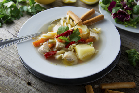 Chicken soup with noodles and vegetables, rustic wooden background. Healthy homemade food. Top view.の写真素材