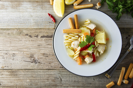 Chicken soup with noodles and vegetables, rustic wooden background. Healthy homemade food. Top view.の写真素材