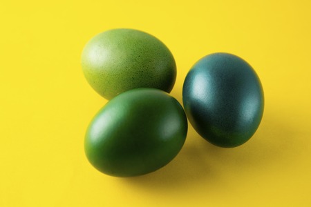Green easter egg isolated on yellow background. Easter holiday concept. Stylish, colorful monochrome backgroundの写真素材
