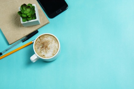 Flat lay, top view office table desk. Workspacewith smartphone, gadget, office supplies, pencil, pen and coffee cup on blue background. space for text.の写真素材