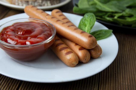 Grilled sausages with sauce ketchup on a wooden tableの写真素材