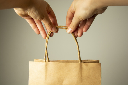 Closeup of female hand holding craft paper package., design mock up. Zero easte concept. No plastic. Protect planet.の写真素材