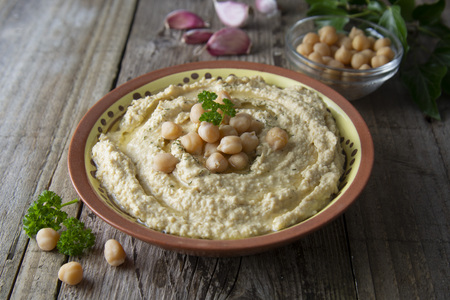 Delicious homemade hummus pasta with olive oil and cheakpeas. Wooden table.の写真素材