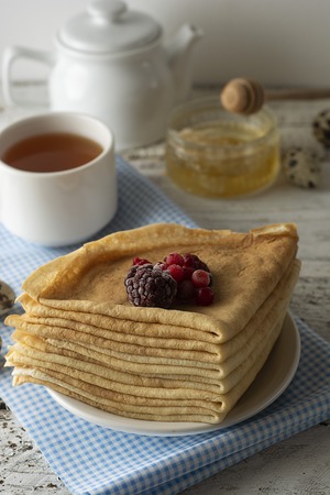 Stack of thin pancakes decorated with strawberries and blueberries. Russian holiday Maslenitsa.