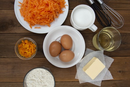 Carrot cake recipe. Making dough for carrot cake, pie, muffins or tart, on kitchen table - eggs, flour, butter, orange, citrus, oil sugarの写真素材