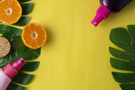 Bottle with suntan cream, on yellow background, decorated with monstera leaves. Summer abstract...