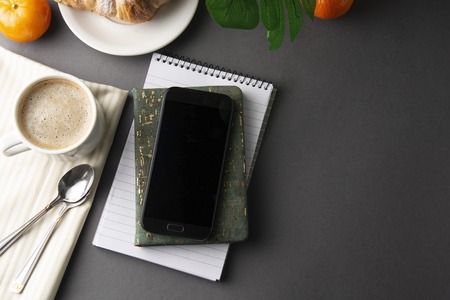 Delicious breakfast coffee with croissant. Heart shaped box. Work table with smart phone. French pastry and cup of coffee. Template for social media. New day.の写真素材