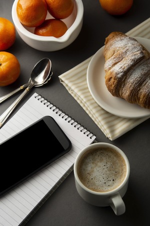 Delicious breakfast coffee with croissant. Heart shaped box. Work table with smart phone. French pastry and cup of coffee. Template for social media. New day.の写真素材