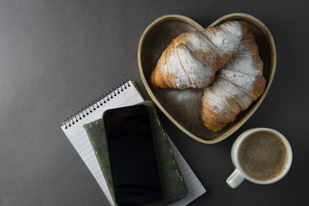 Delicious breakfast coffee with croissant. Heart shaped box. Work table with smart phone. French pastry and cup of coffee. Template for social media. New day.の写真素材