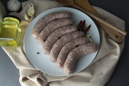 Raw, uncooked pork, meat sausages on slate, with herbs and spices. Meat food. Sausages isolated