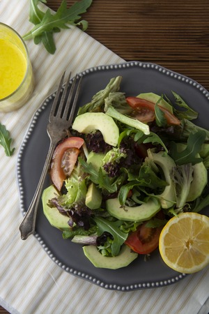 Organic Healthy salad mix of iceberg, spinach, avocado and cucumber with olive oil, tomato and...