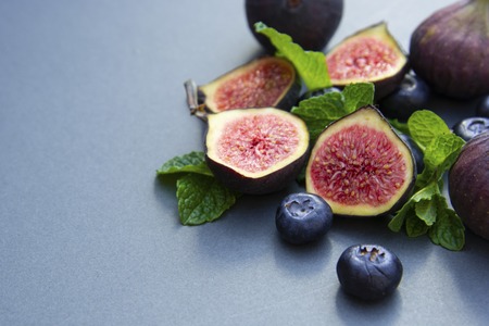 Fresh figs with mint and blueberries. Beautifulf berry, fruit background, frame for design with copy space. Flat lay.の写真素材
