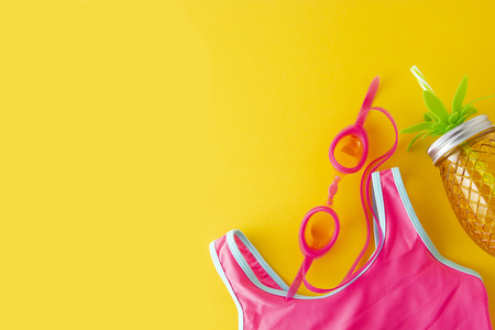 Flat lay composition, summer colorful background with pink swimsuit and beach objects on yellow background. Copy space for text.の写真素材