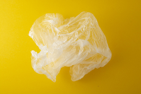Clear disposable plastic bag on yellow background. Zero waste concept. No plastic. Save planetの写真素材