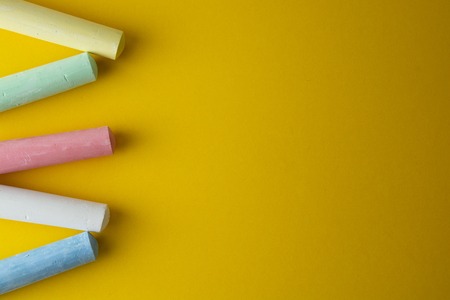Abstract colorful chalks over yellow background with copy space. Education template. Creative childhod, business concept. Top view, copy space.の写真素材